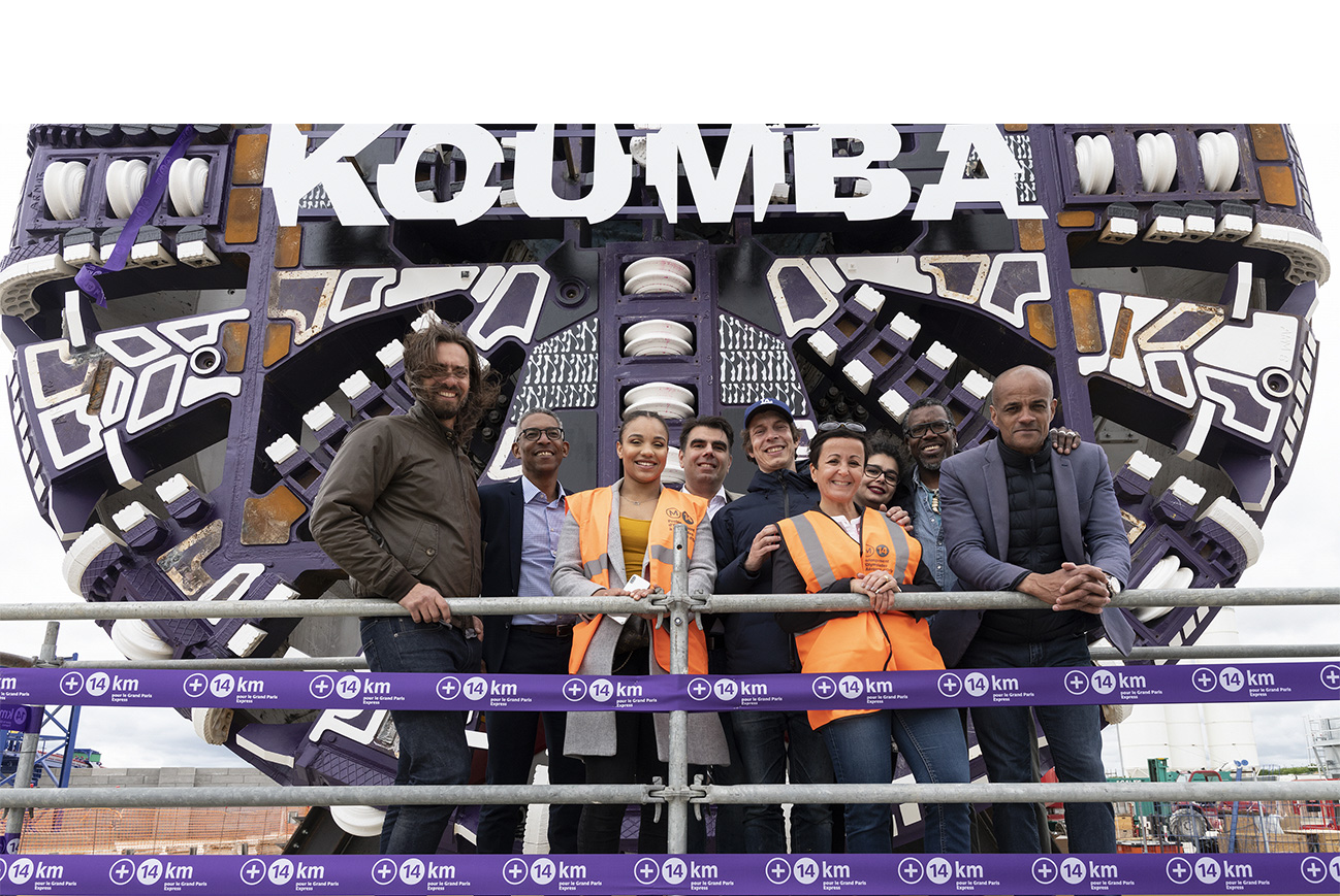 Photo de Koumba Larroque entourée de l’équipe ayant réalisé un travail artistique sur la roue de coupe du tunnelier et de l’équipe projet le jour du baptême.